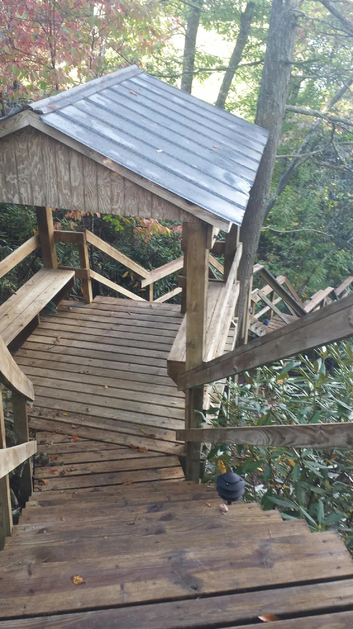 Metal roofed shelter over wooden steps on a wooded walkway — Skylight Repair & Installation work by our crew in Fair Haven