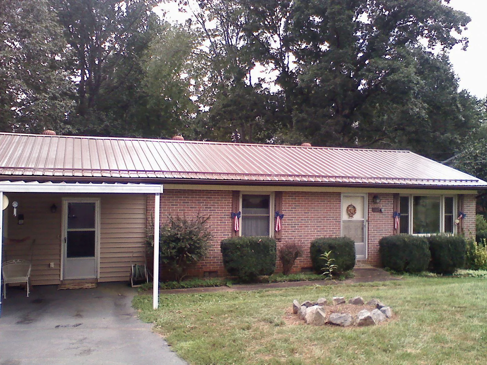 Bronze metal roof and carport on a brick ranch home — Roof Repair work by our crew in Fair Haven