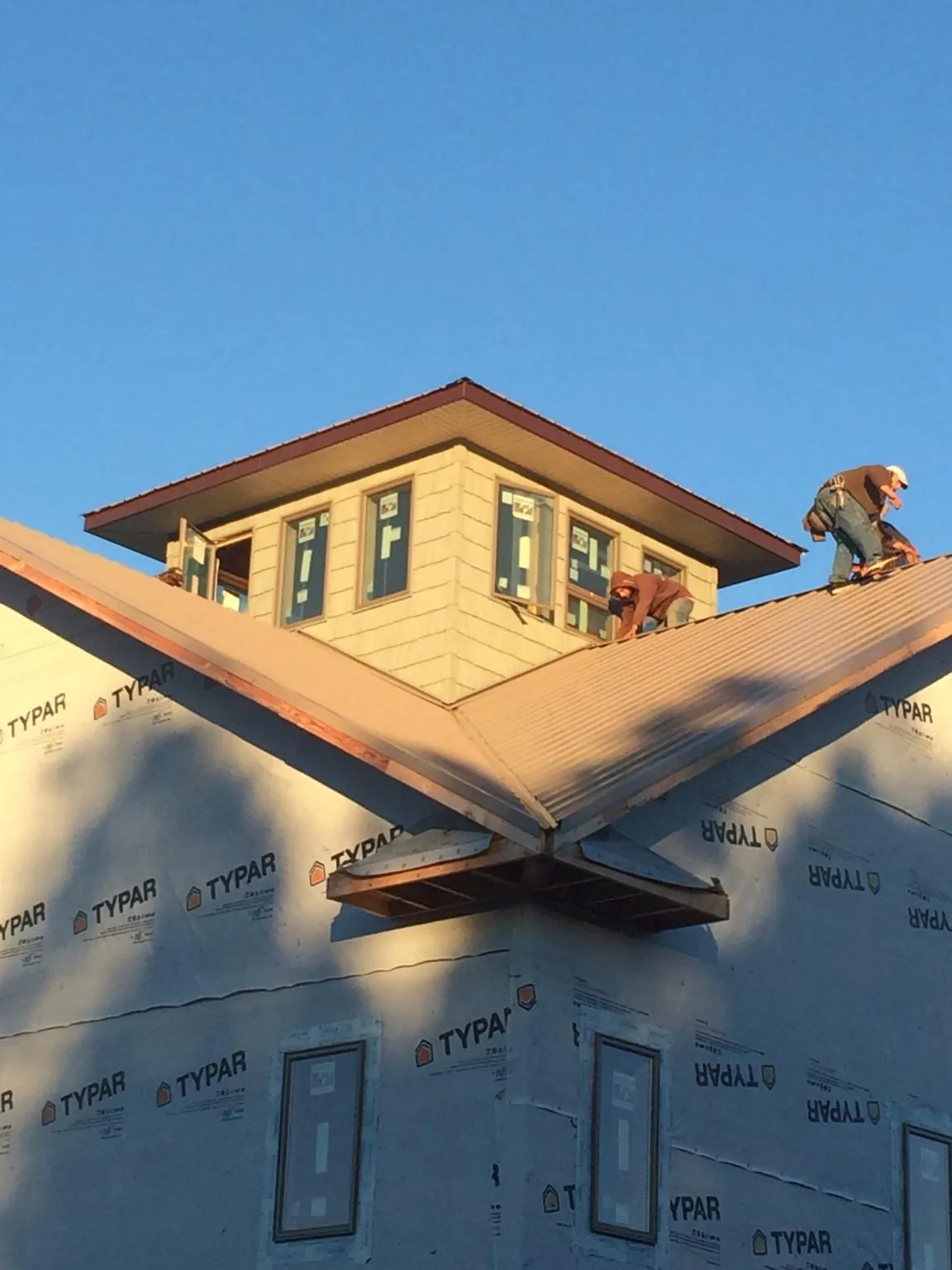 Roofers working around a rooftop cupola on a new metal roof at sunset — Roof Waterproofing in Fair Haven by Roofing Brothers